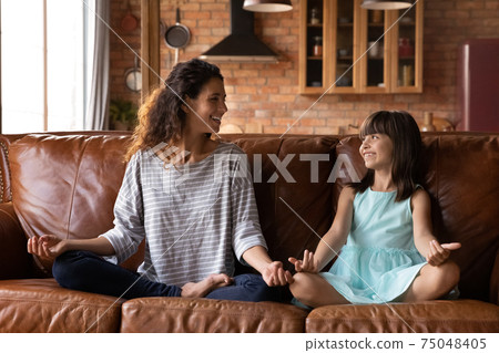 Happy Latino mom and little girl practice yoga at home 75048405