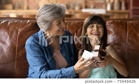 Loving grandmother congratulate excited little granddaughter with birthday Loving grandmother congratulate excited little granddaughter with birthday 75048426