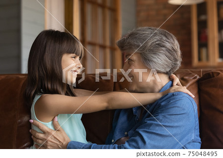 Smiling senior grandmother and small granddaughter hugging Smiling senior grandmother and small granddaughter hugging 75048495