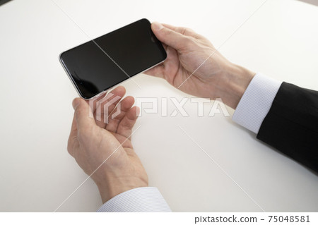 Both hands of a man holding a smartphone and mobile phone 75048581