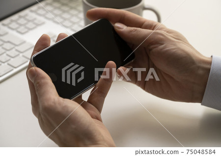 Both hands of a man holding a smartphone and mobile phone 75048584