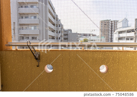 The balcony of an apartment with a bird net 75048586