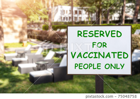 Text plate RESERVED FOR VACCINATED PEOPLE ONLY at luxury hotel pool beach resort area empty loungers on summer day. New normal travel and vacation concept. Covid-19 pandemic restriction and limit Text plate RESERVED FOR VACCINATED PEOPLE ONLY at luxury hotel pool beach resort area empty loungers on summer day. New normal travel and vacation concept. Covid-19 pandemic restriction and limit 75048758