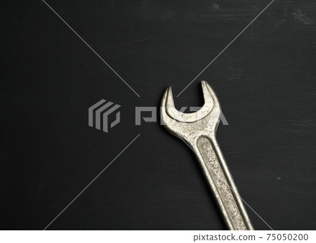 metal wrench for nuts on a black background, close up metal wrench for nuts on a black background, close up 75050200