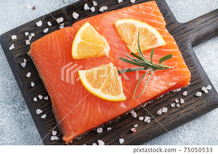 Salmon fillet, red salted fish on a wooden chopping Board. Lemon, rosemary spices. 75050533