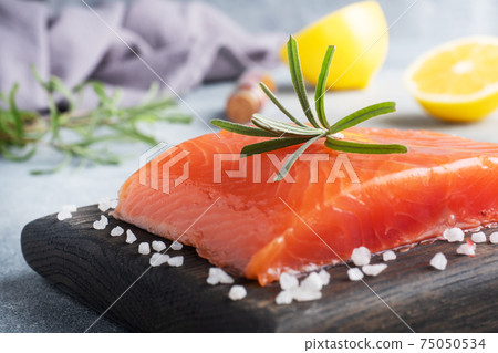 Salmon fillet, red salted fish on a wooden chopping Board. Lemon, rosemary spices. 75050534