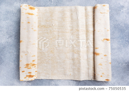 Thin Armenian lavash rolled into a roll. Texture of natural bread baking. 75050535