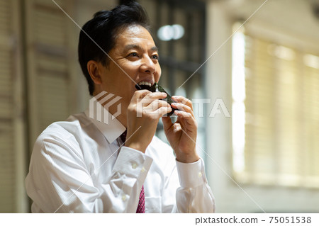 A man eating rice balls A man eating rice balls 75051538
