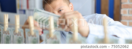 Man is holding one hundred dollars in his hands rest of bills are hanging on clothespins. 75052062