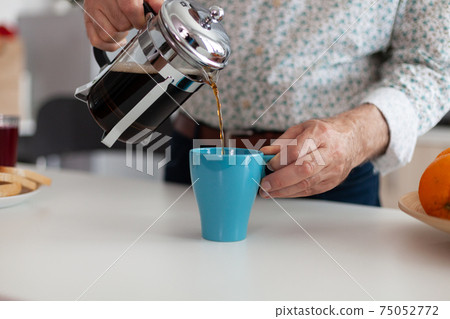 Senior man spilling hot drink after preparing coffee using french press Senior man spilling hot drink after preparing coffee using french press 75052772