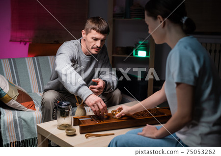 The guy made a delicious tea for his girlfriend according to an old traditional chinese recipe. The ritual of oriental tea drinking at the table at home. 75053262