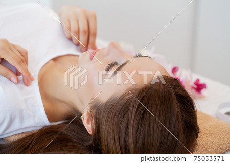 Beautiful young woman relaxing with hand massage at beauty spa salon. 75053571