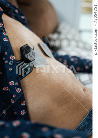 sitting and using muscle stimulation device sitting and using muscle stimulation device 75054751