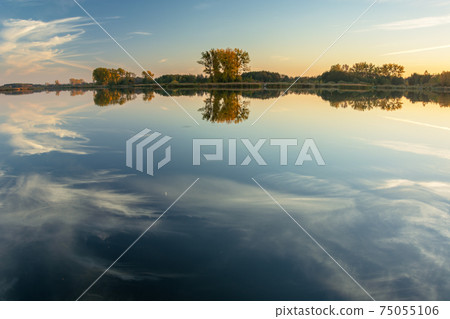Reflection of white clouds in the water of a calm lake Reflection of white clouds in the water of a calm lake 75055106