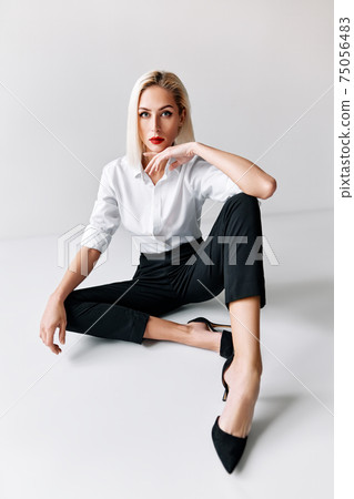 Portrait of daring trendy woman posing on white studio background. sitting on floor 75056483