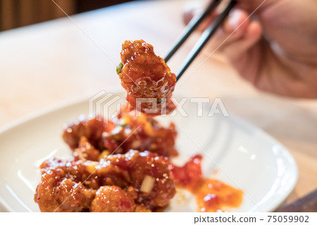 Chopsticks holding Korean fried chicken. 75059902