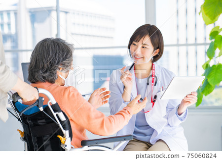 A doctor examining an elderly person in a wheelchair 75060824