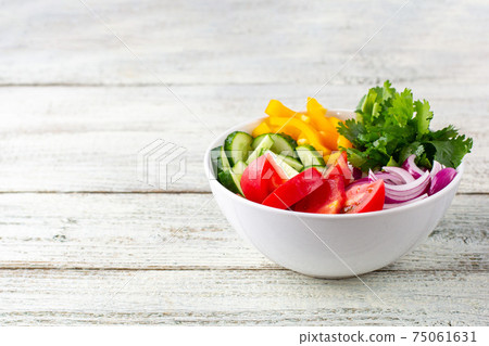 Plate of rainbow salad with different vegetables and herbs in white bowl on white wooden background 75061631
