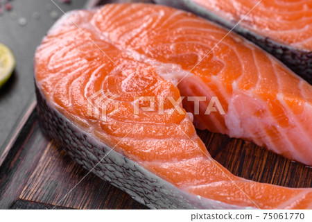 Fresh raw salmon steak with spices and herbs prepared for grilled baking Fresh raw salmon steak with spices and herbs prepared for grilled baking 75061770