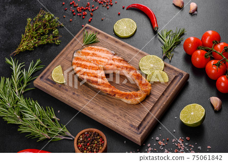 Fresh cooked delicious salmon steak with spices and herbs baked on a grill Fresh cooked delicious salmon steak with spices and herbs baked on a grill 75061842