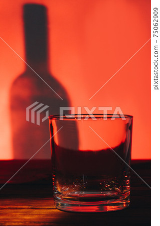 Low glass for scotch or whiskey and shadow of bottle. Low glass for scotch or whiskey and shadow of bottle. 75062909