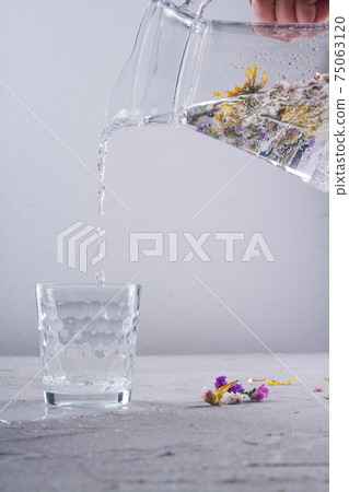 Pouring fresh clean water from a glass jug. 75063120