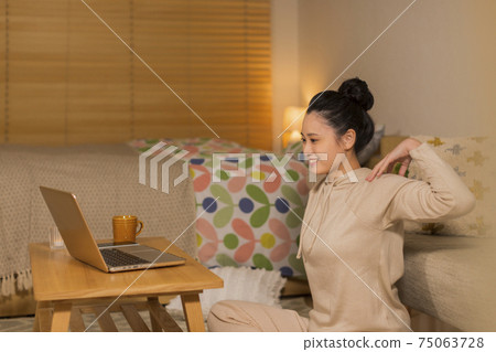 A woman doing body care while looking at a computer A woman doing body care while looking at a computer 75063728
