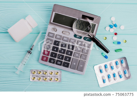 Stethoscope and magnifier over a calculator symbol for health care costs or medical insurance. Stethoscope and magnifier over a calculator symbol for health care costs or medical insurance. 75063775