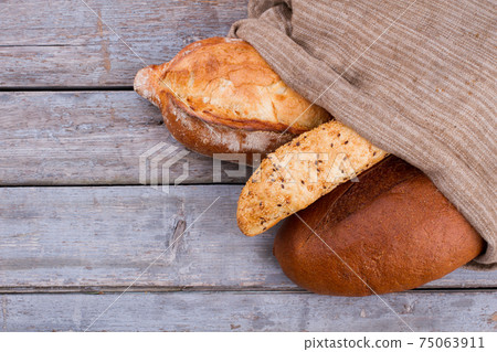 Different types of bread in burlap bag. 75063911