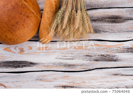 Bread and wheat ears on wooden background. 75064048