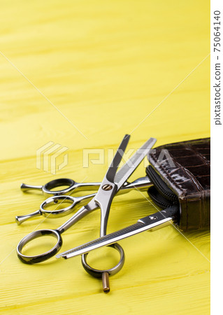 Professional steel hairdresser scissors on yellow background. Professional steel hairdresser scissors on yellow background. 75064140