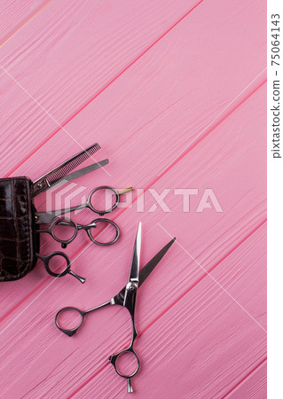 Hairdresser scissors on pink wooden table. Hairdresser scissors on pink wooden table. 75064143