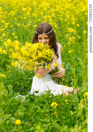 A child in a blooming field with yellow flowers. 75064339