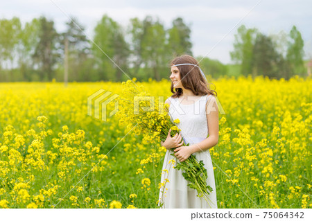 A child in a blooming field with yellow flowers. 75064342