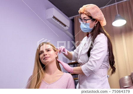 female doctor trichologist conducts mesotherapy or plasma therapy for young woman patient 75064379