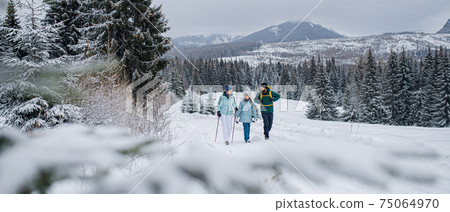 Family with small daughter on a walk outdoors in winter nature, Tatra mountains Slovakia. Family with small daughter on a walk outdoors in winter nature, Tatra mountains Slovakia. 75064970