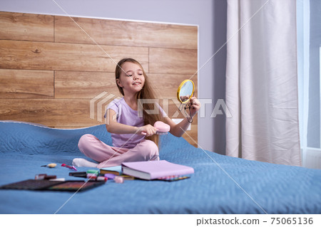 Child girl sitting on bed and playing with moms cosmetics, at home Child girl sitting on bed and playing with moms cosmetics, at home 75065136