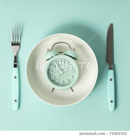 Composition with cutlery, plate and alarm clock on color background. Diet concept Composition with cutlery, plate and alarm clock on color background. Diet concept 75065502