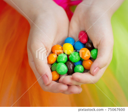 Colored candies in children's hands 75067600