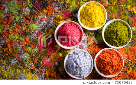 Holi festival celebration. Traditional Indian Holi colours powder decoration with paints. Top view of Organic Gulal colors in bowls ondark background. Holi festival celebration. Traditional Indian Holi colours powder decoration with paints. Top view of Organic Gulal colors in bowls ondark background. 75070455