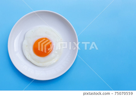 Fried egg on blue background. 75070559