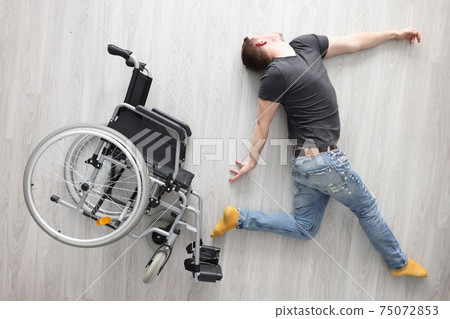 Disabled man lies on floor next to wheelchair Disabled man lies on floor next to wheelchair 75072853