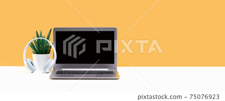 Laptop with wireless headphones on white desk orange wall Laptop with wireless headphones on white desk orange wall 75076923