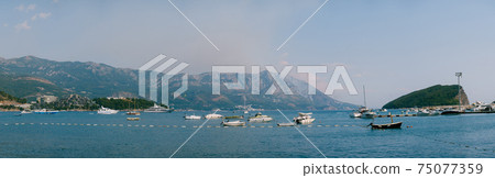 Forest fire in the mountains of Montenegro, over the island of Sveti Stefan. View from the sea through yachts and boats from Budva. 75077359
