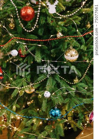 Decorated Christmas tree with garland, balls and beads. 75077661