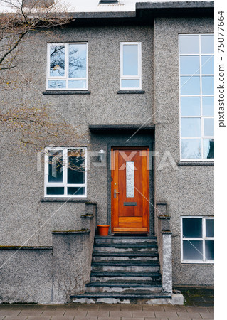 The entrance is from a wooden door into a modern two-story building with plastic windows of various sizes and steps with columns. The entrance is from a wooden door into a modern two-story building with plastic windows of various sizes and steps with columns. 75077664