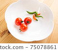 Petit tomatoes and two-colored red pepper on a white plate on a white wooden table 75078861