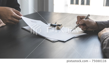 Female attendant handed over the rental car key to the customer who signed the contract and the terms of the agreement on the document, Car rental service concept. Female attendant handed over the rental car key to the customer who signed the contract and the terms of the agreement on the document, Car rental service concept. 75080116