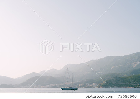 Yacht on a background of mountains on a foggy summer morning. Yacht on a background of mountains on a foggy summer morning. 75080606