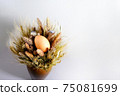Easter eggs in a nest of dried flowers. On a gray background. 75081699
